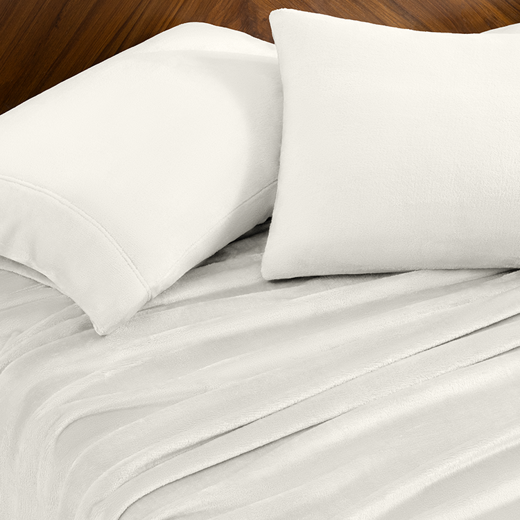 White bed sheets and pillows on a wooden surface