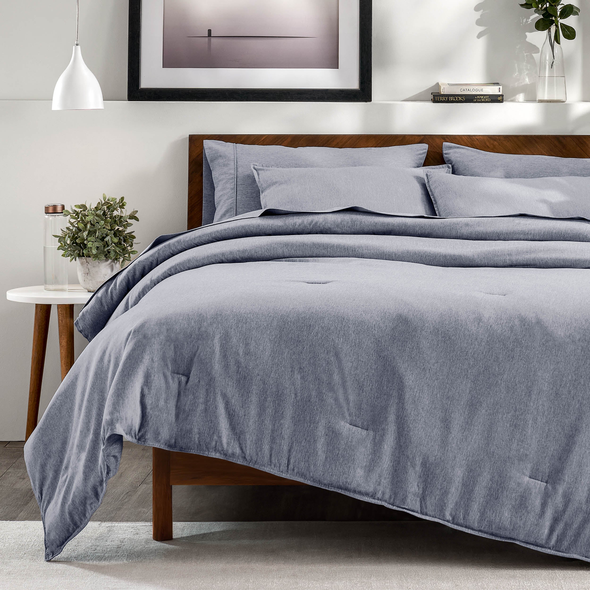 A bedroom with a side table, decor and a neatly made bed
