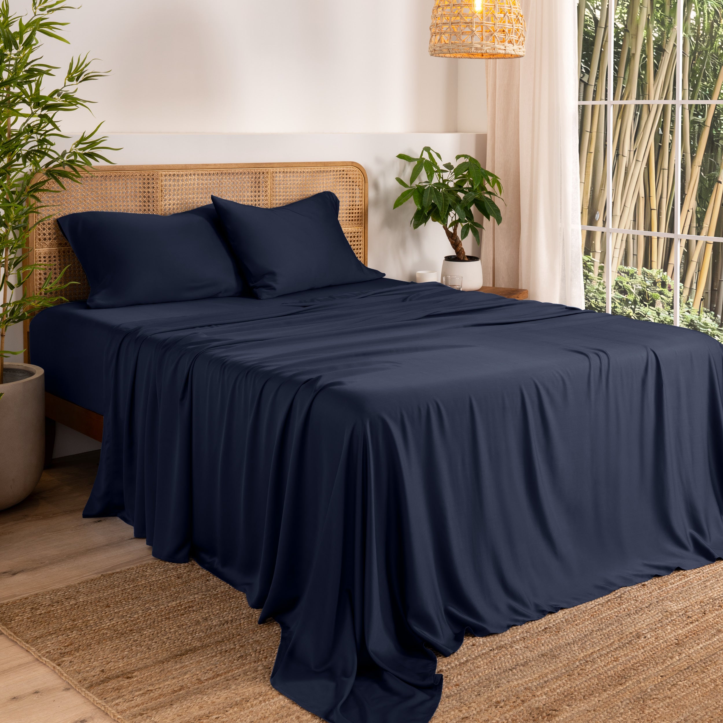 Bamboo sheets on a bed in a bedroom with plants and a lamp.