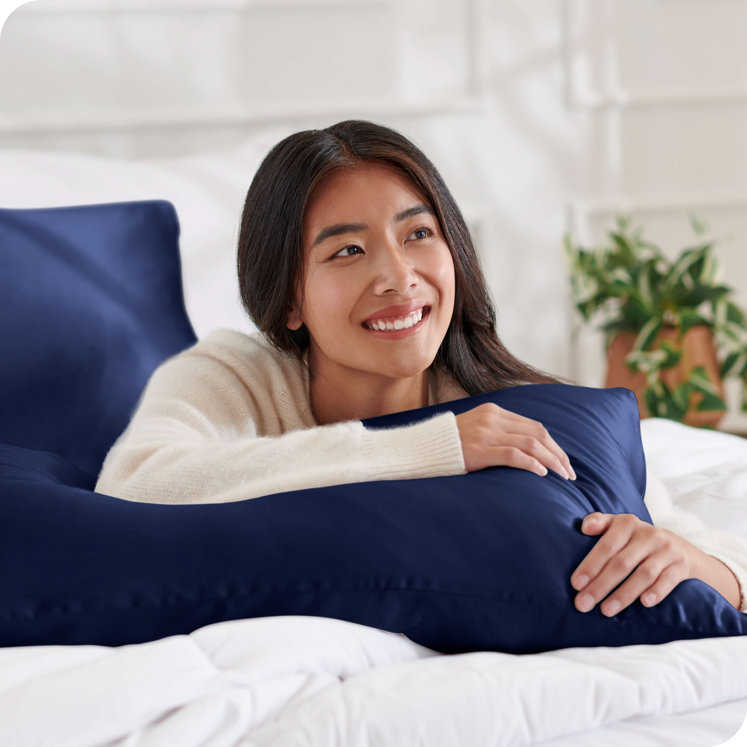 A woman on a bed with a silk pillowcase covered pillow