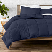 Comforter set on a bed with a white brick wall and plant in the background