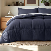 Comforter on a bed in a bedroom setting with a wooden nightstand and decorative items.