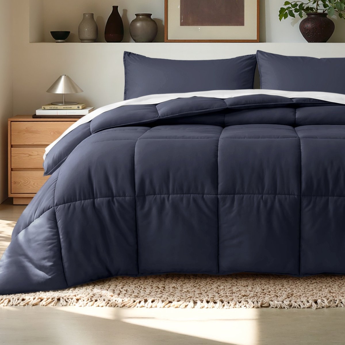 Comforter on a bed in a bedroom setting with a wooden nightstand and decorative items.