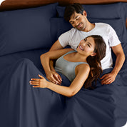 A couple is relaxing in bed with pillows behind them