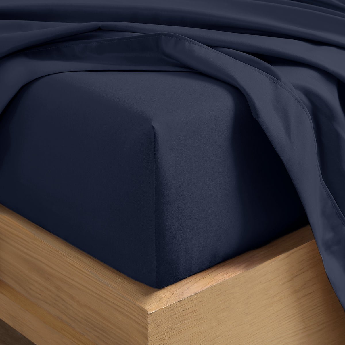 Close up of the corner of a mattress with a fitted sheet and flat sheet on it