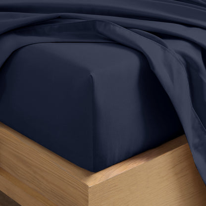 Close up of the corner of a mattress with a fitted sheet and flat sheet on it
