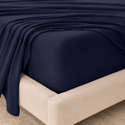 Fitted sheet and top sheet on a mattress with a beige bed frame