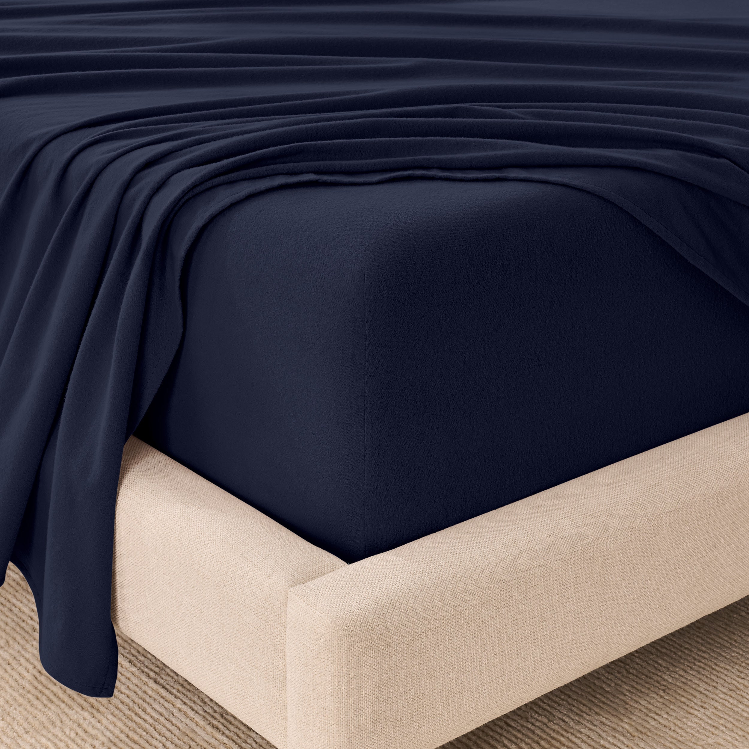 Fitted sheet and top sheet on a mattress with a beige bed frame