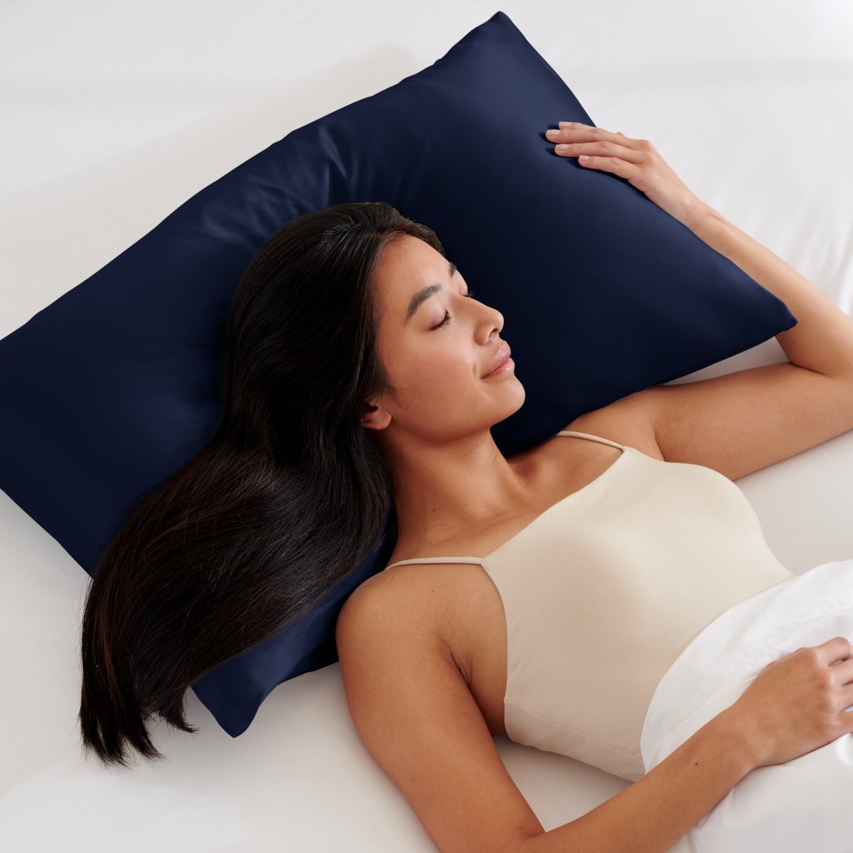 Woman lying on a bed with a pillow covered with a satin pillowcase