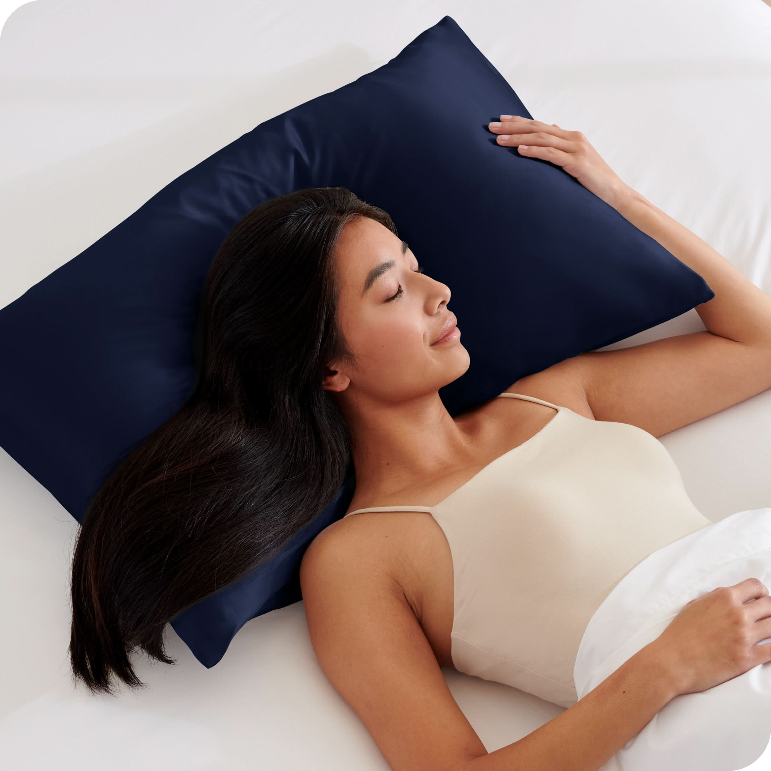 A woman is sleeping on a pillow with a satin pillowcase