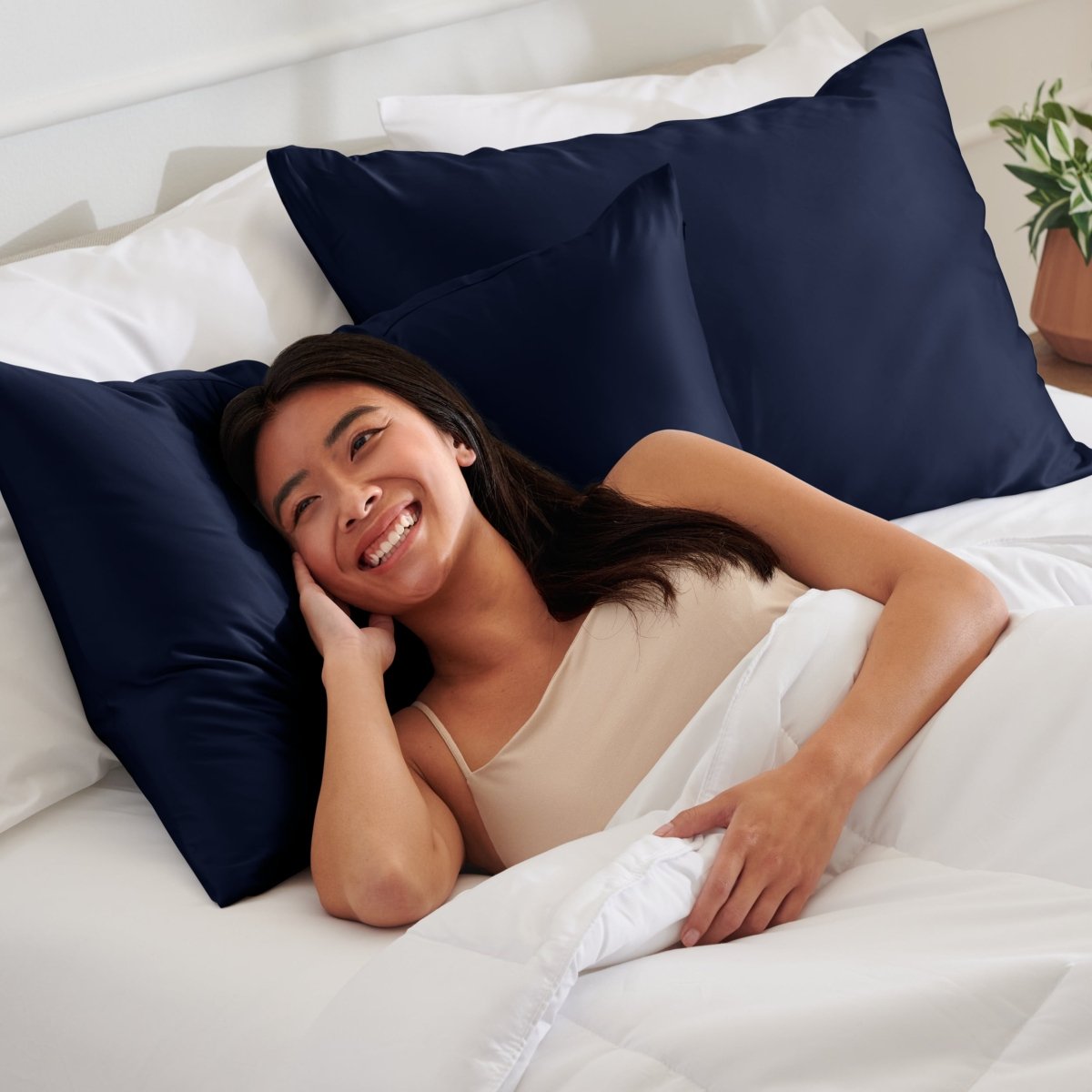 Woman lying on a bed with satin pillows and white bedding