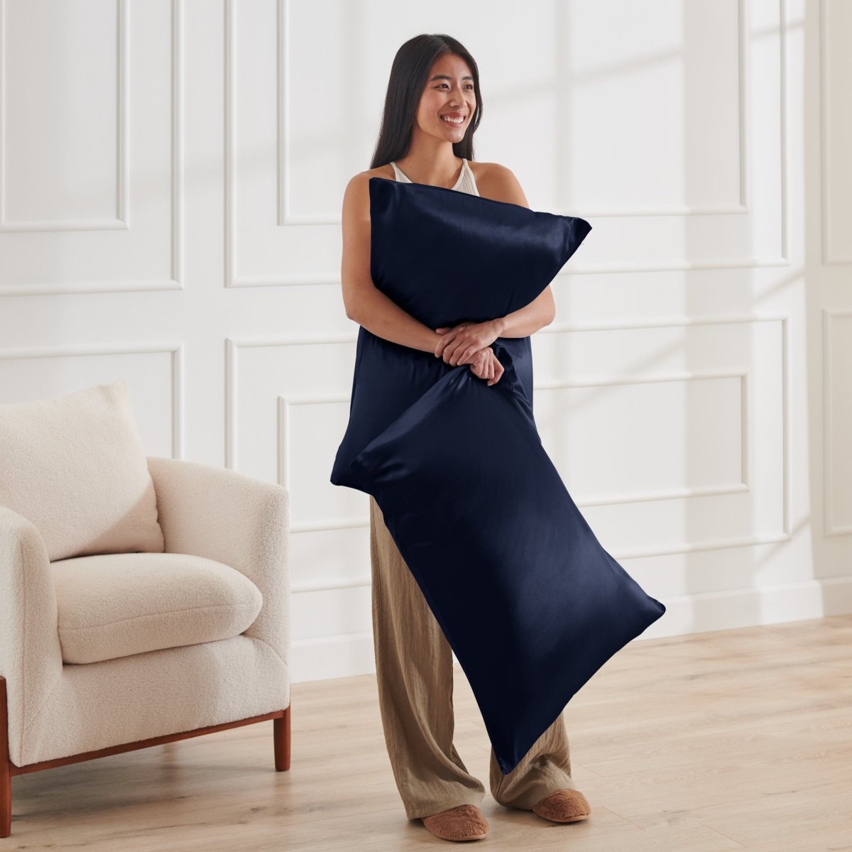 Woman holding 2 pillows with satin pillowcases on them