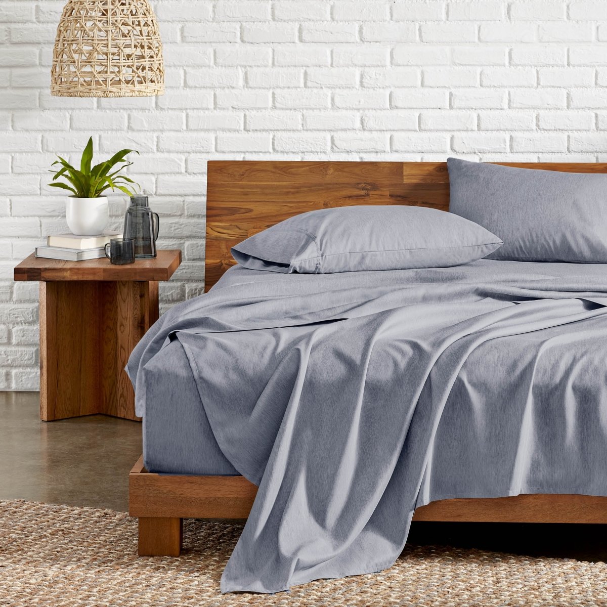 Bedroom with wooden bed, nightstand, and white brick wall.