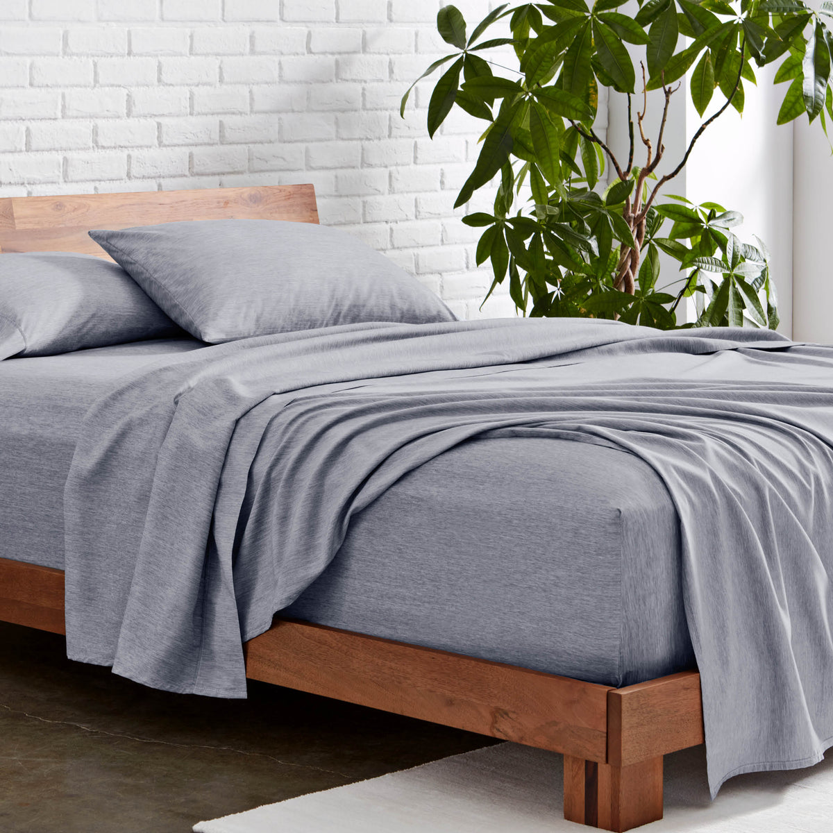 Microfiber sheet set on a wooden bed with a plant in the background