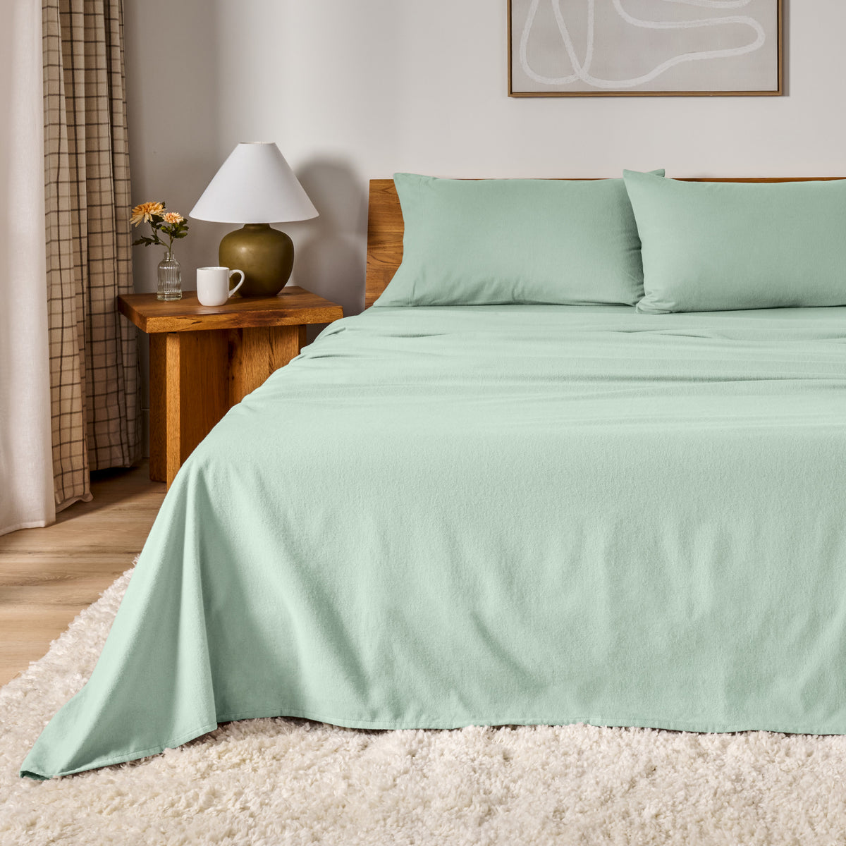 A bed dressed in flannel sheet set in a bedroom with a wooden headboard, bedside table and lamp