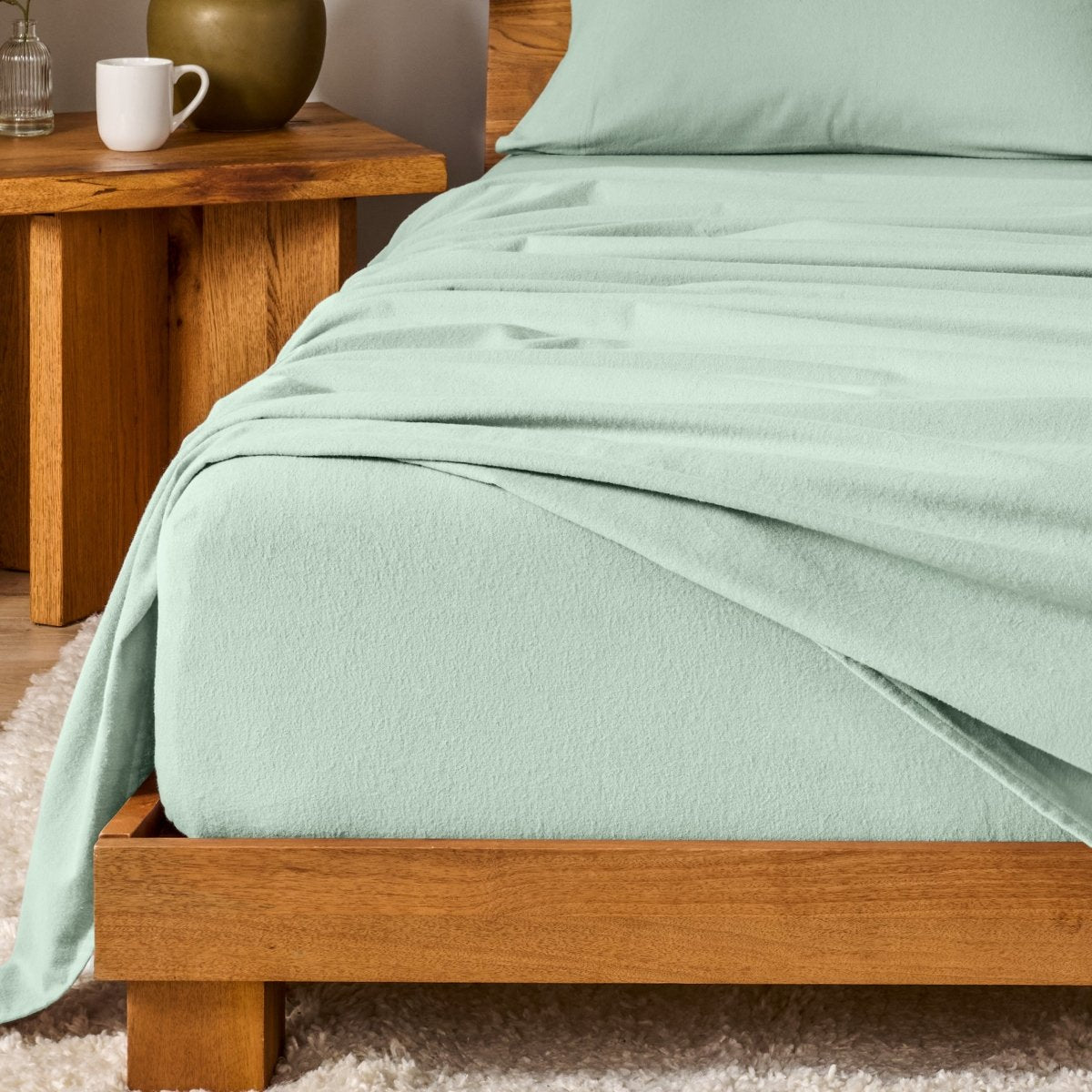 Bed with flannel bedding and wooden headboard and nightstand next to it.