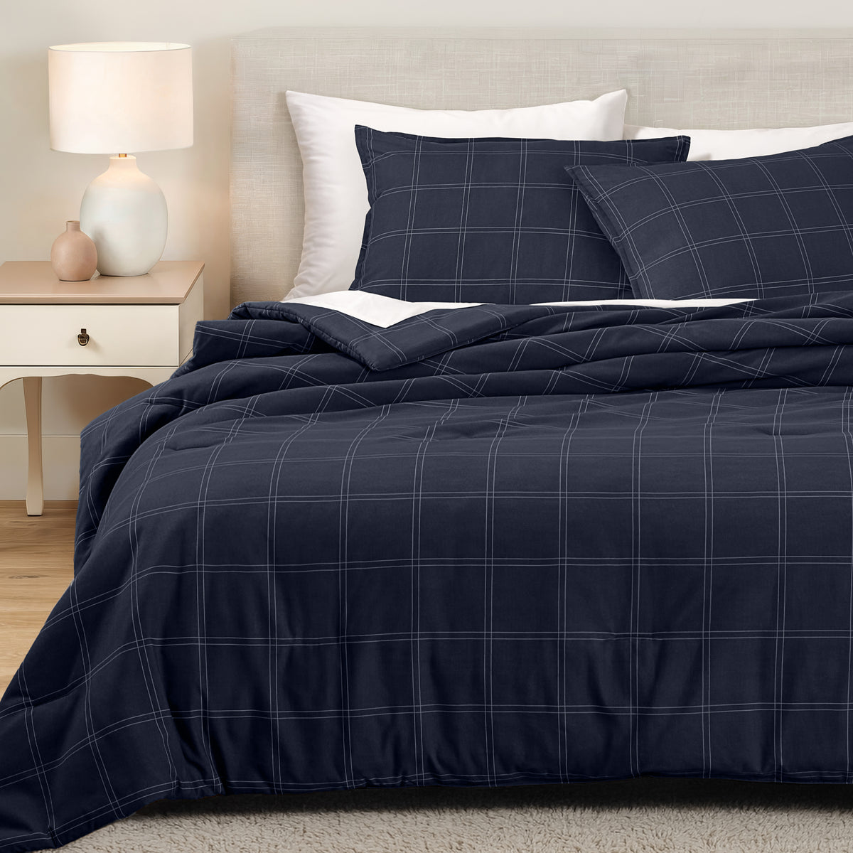 Bedding set on a bed in a bedroom with a side table and lamp.
