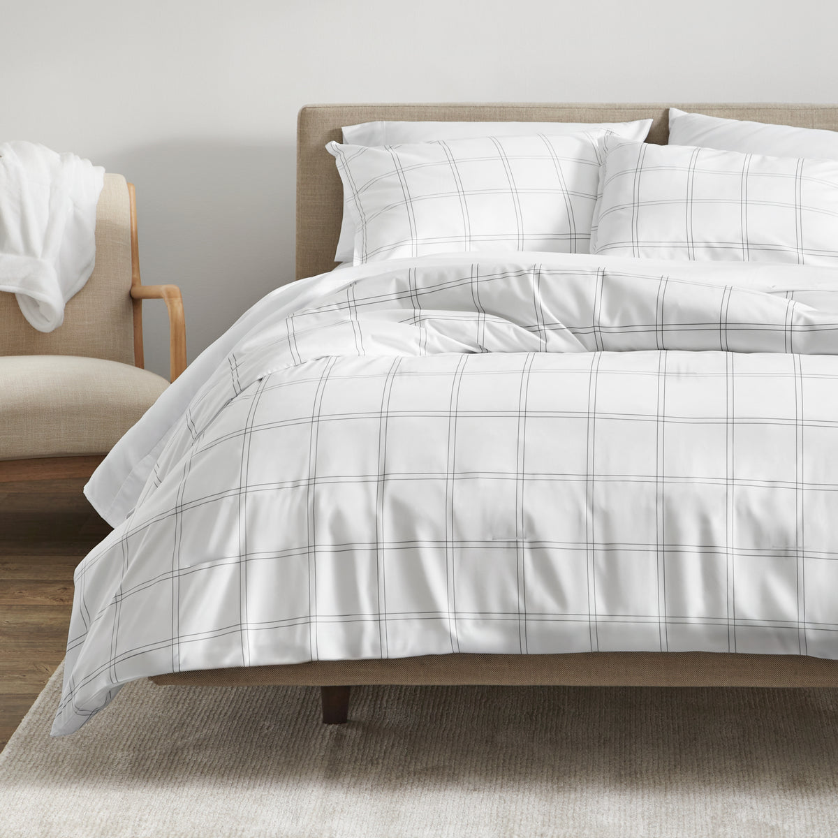 Bedding set on a bed in a bedroom with a side table and lamp.