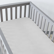 Gray crib with a fitted sheet on the mattress