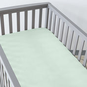 Gray crib with a fitted sheet on the mattress