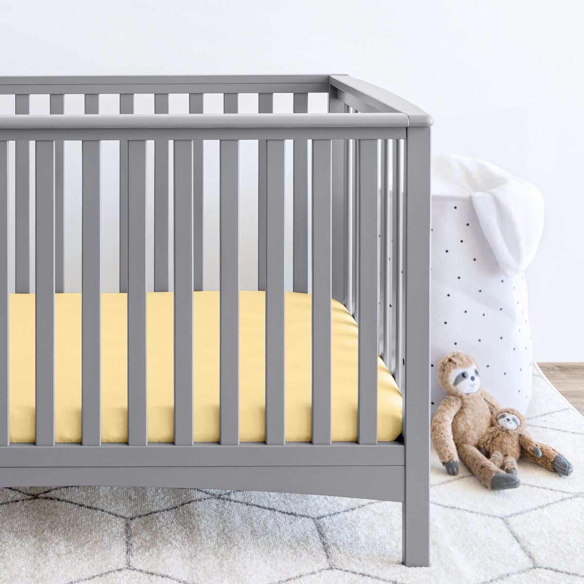 Gray crib with stuffed animals on the floor next to it