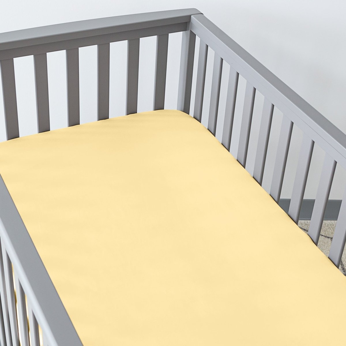 Gray crib with a fitted sheet on the mattress