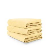 Stack of yellow folded crib sheets on a white background