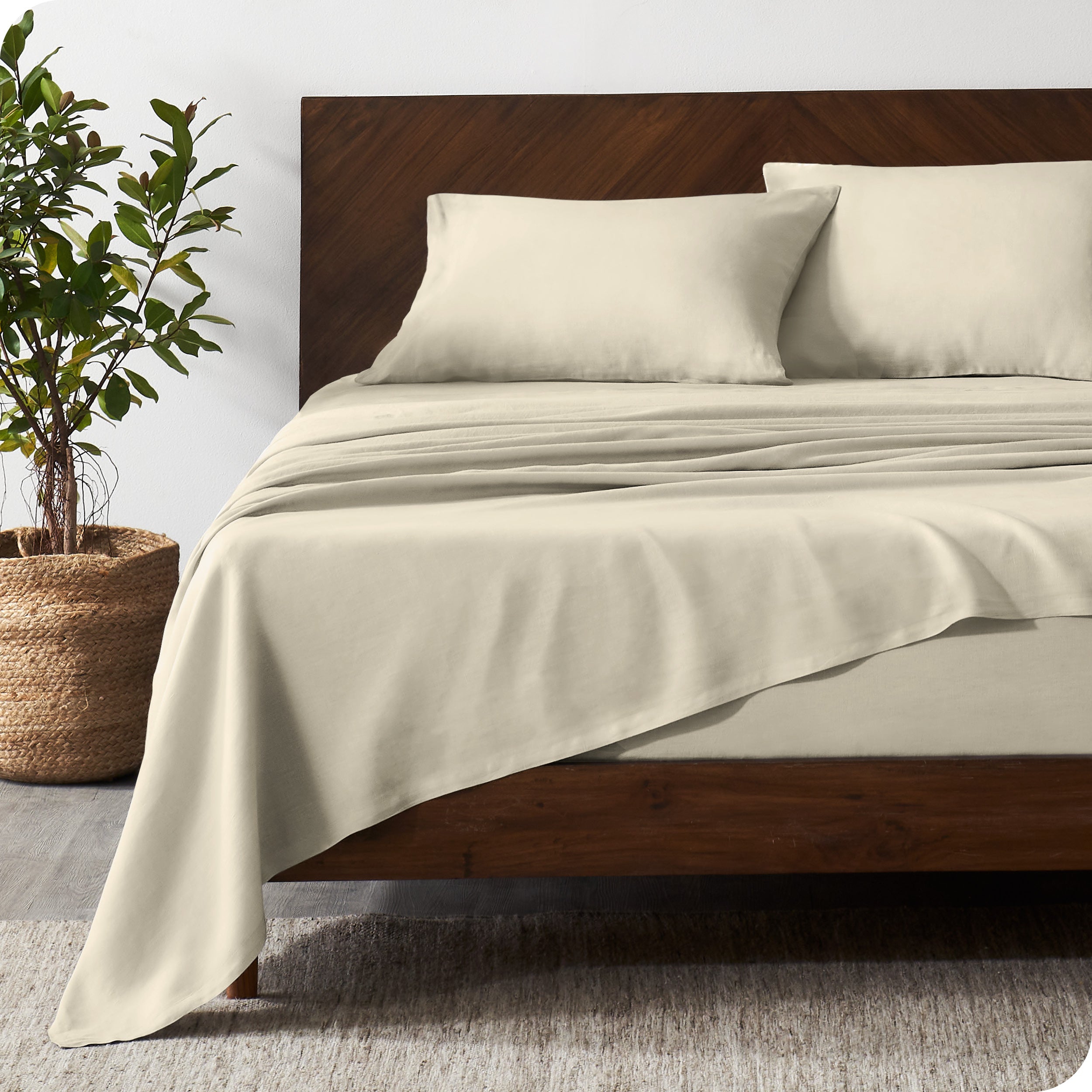 Dark wooden bed frame with natural color linen sheets on the mattress