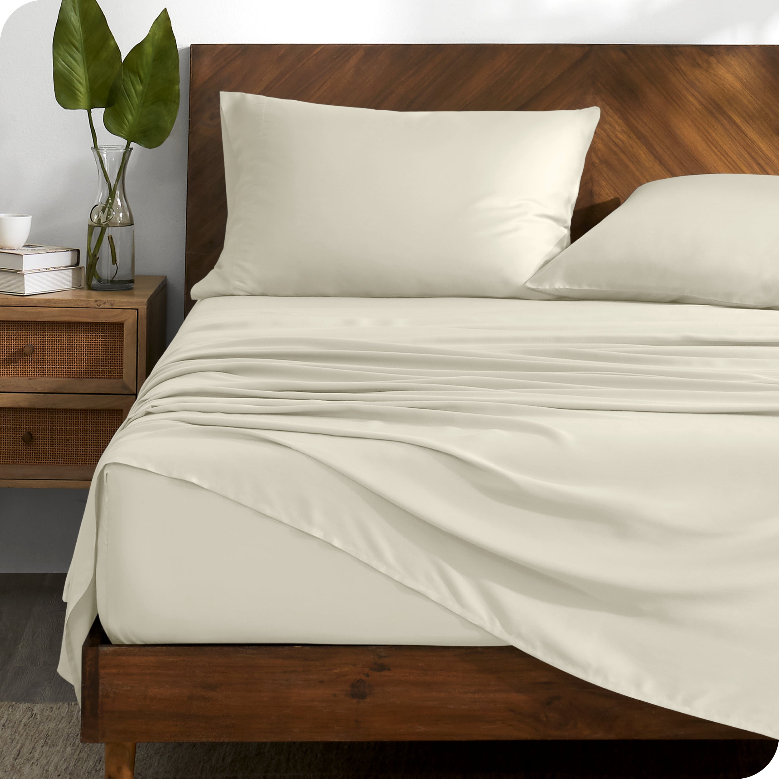 TENCEL™ sheet set on a bed with the flat sheet loosely draped over the top. The mattress is on a wooden bed frame.