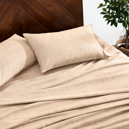 Oatmeal color bedding set on a bed with a wooden headboard and plant in the background