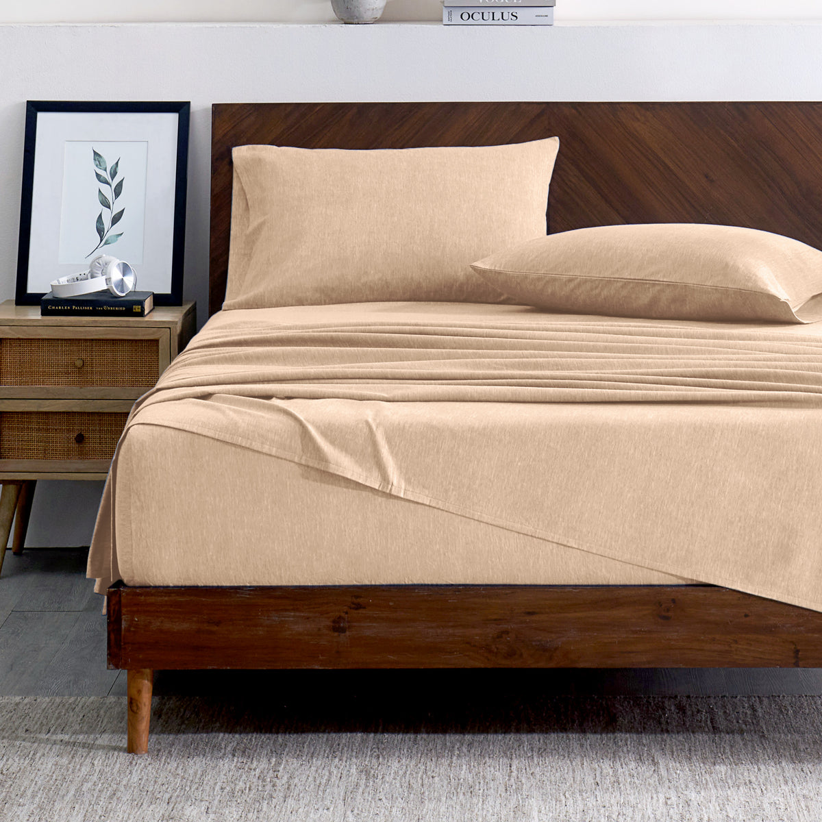 Oatmeal color bedding set on a bed with a wooden headboard and plant in the background