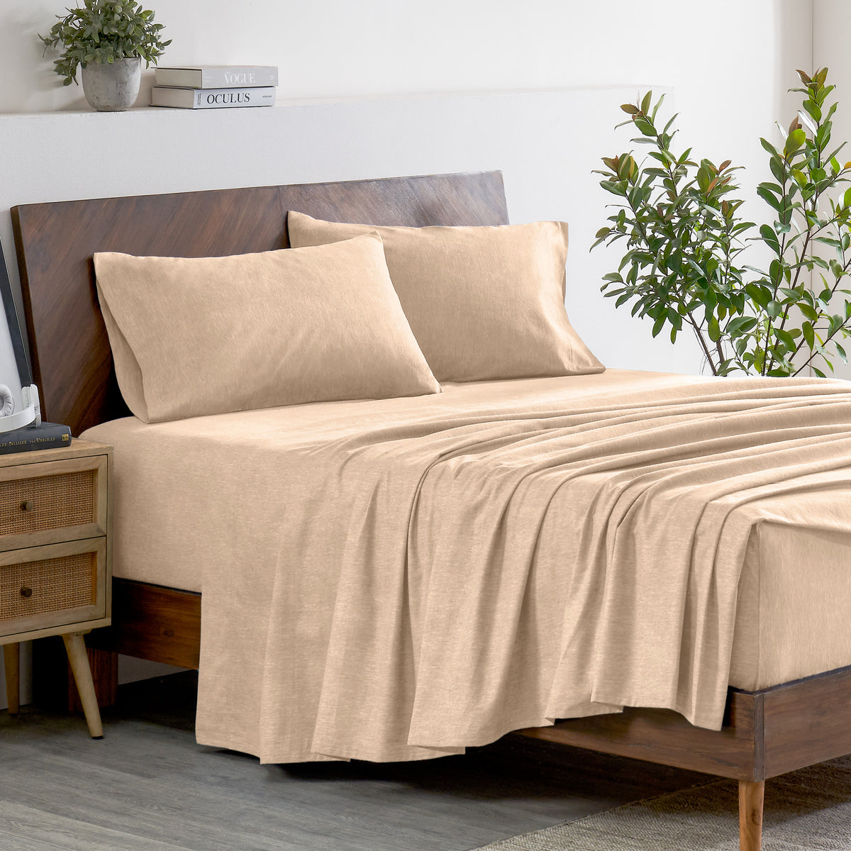 Oatmeal color bedding set on a bed with a wooden headboard and plant in the background