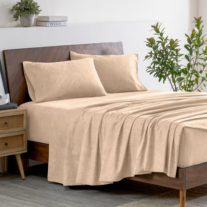 Oatmeal color bedding set on a bed with a wooden headboard and plant in the background