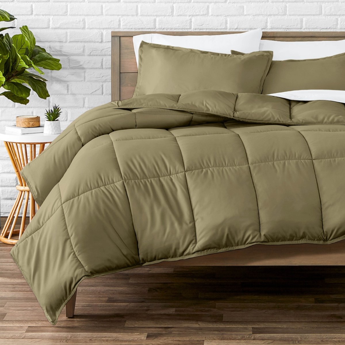 Comforter set on a bed with a white brick wall and plant in the background