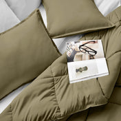 Comforter and pillows on a bed with a magazine and glasses.