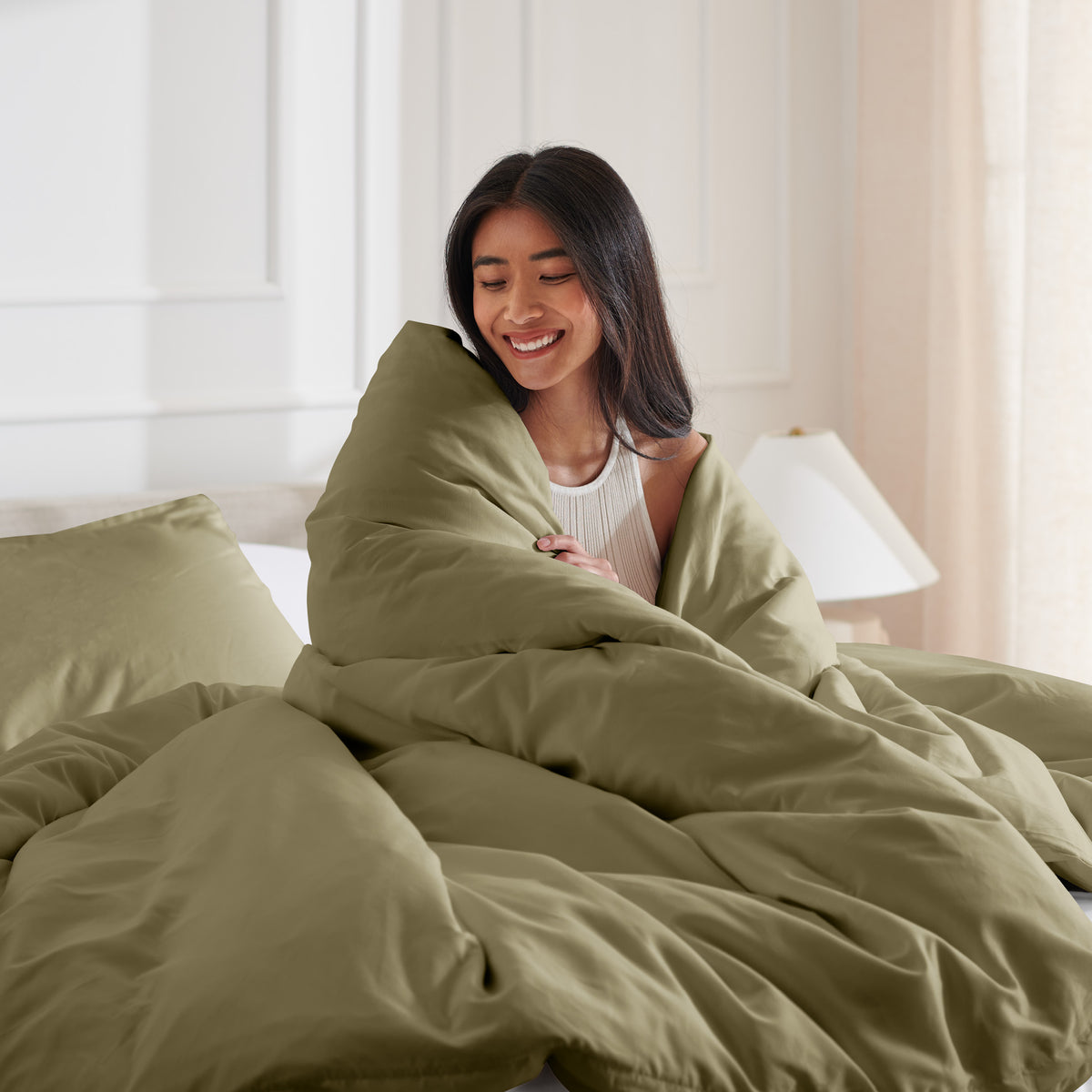 Woman smiling under duvet cover set in a bedroom setting