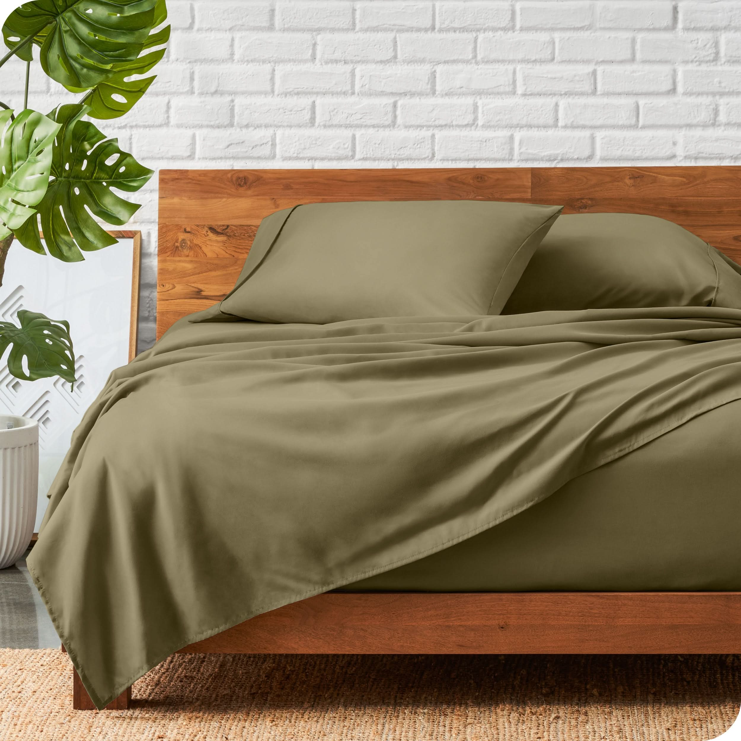 A wooden bed frame with a microfiber sheet set on the mattress.