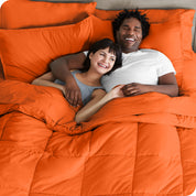 A couple is lying in bed with a comforter and sheets over them