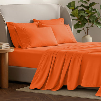 Bed sheets and pillows on a bed with a plant and side table in the background.