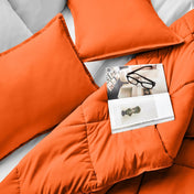 Comforter and pillows on a bed with a magazine and glasses.