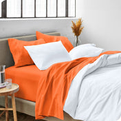A side view of a bed made with microfiber sheets and a white duvet cover