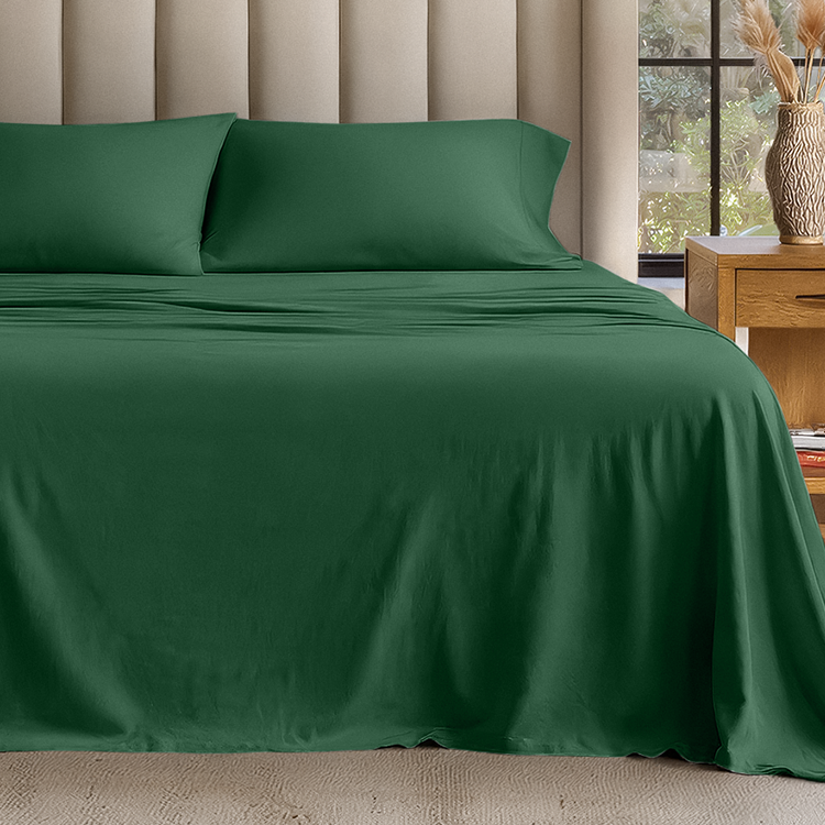 Green bed sheets and pillowcases on a bed in a bedroom setting.