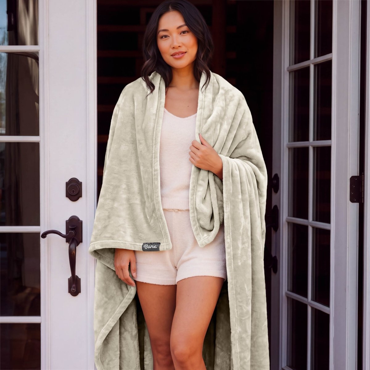 A woman standing with a microplush blanket wrapped around her