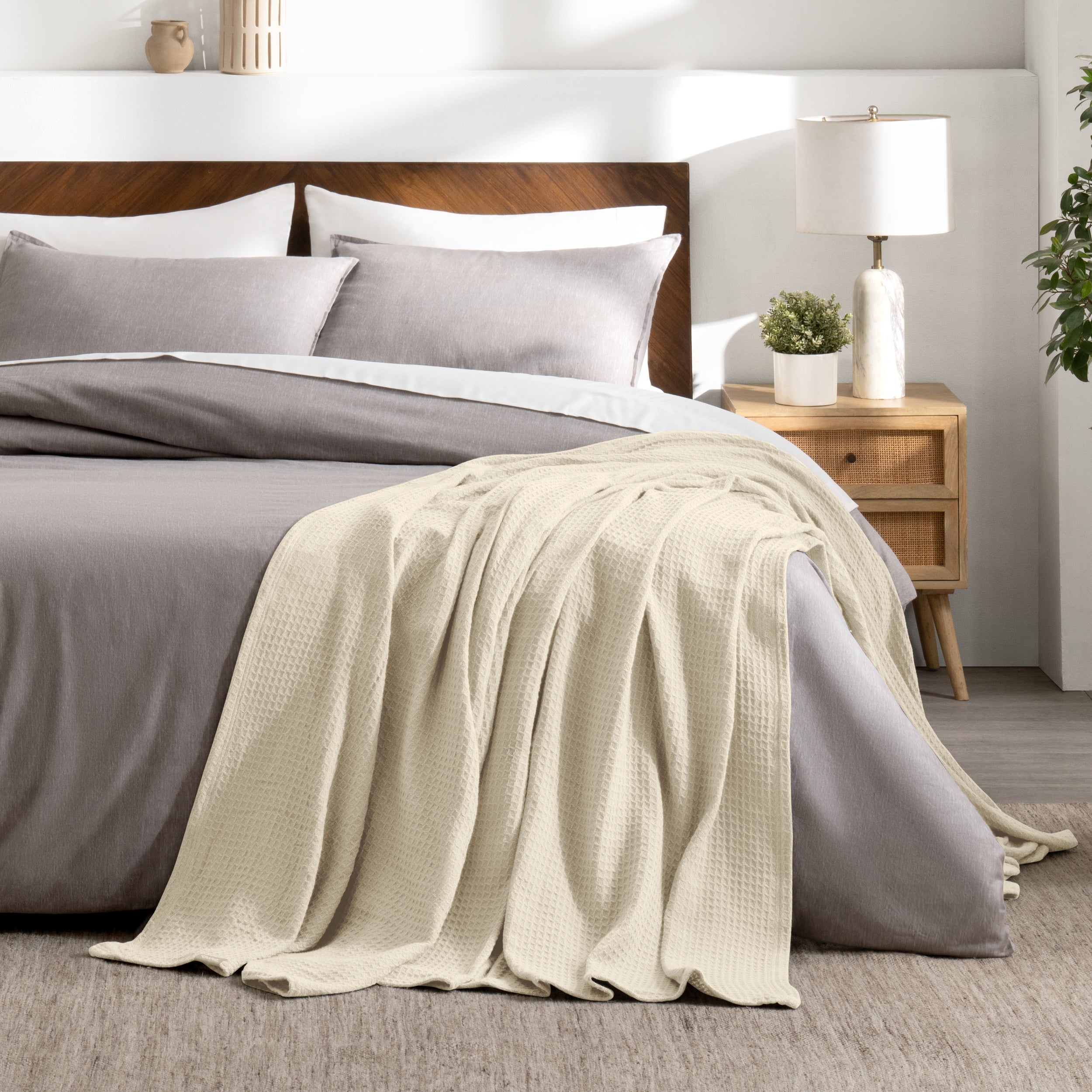 Bed with gray bedding and a throw blanket in a bedroom setting.