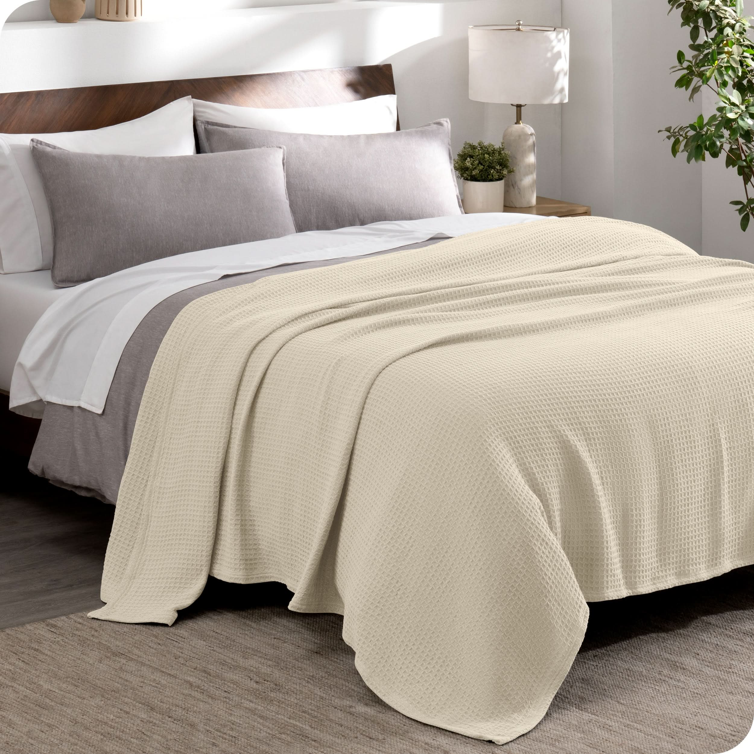 A cotton waffle blanket draped over the top of a bed made with a duvet set