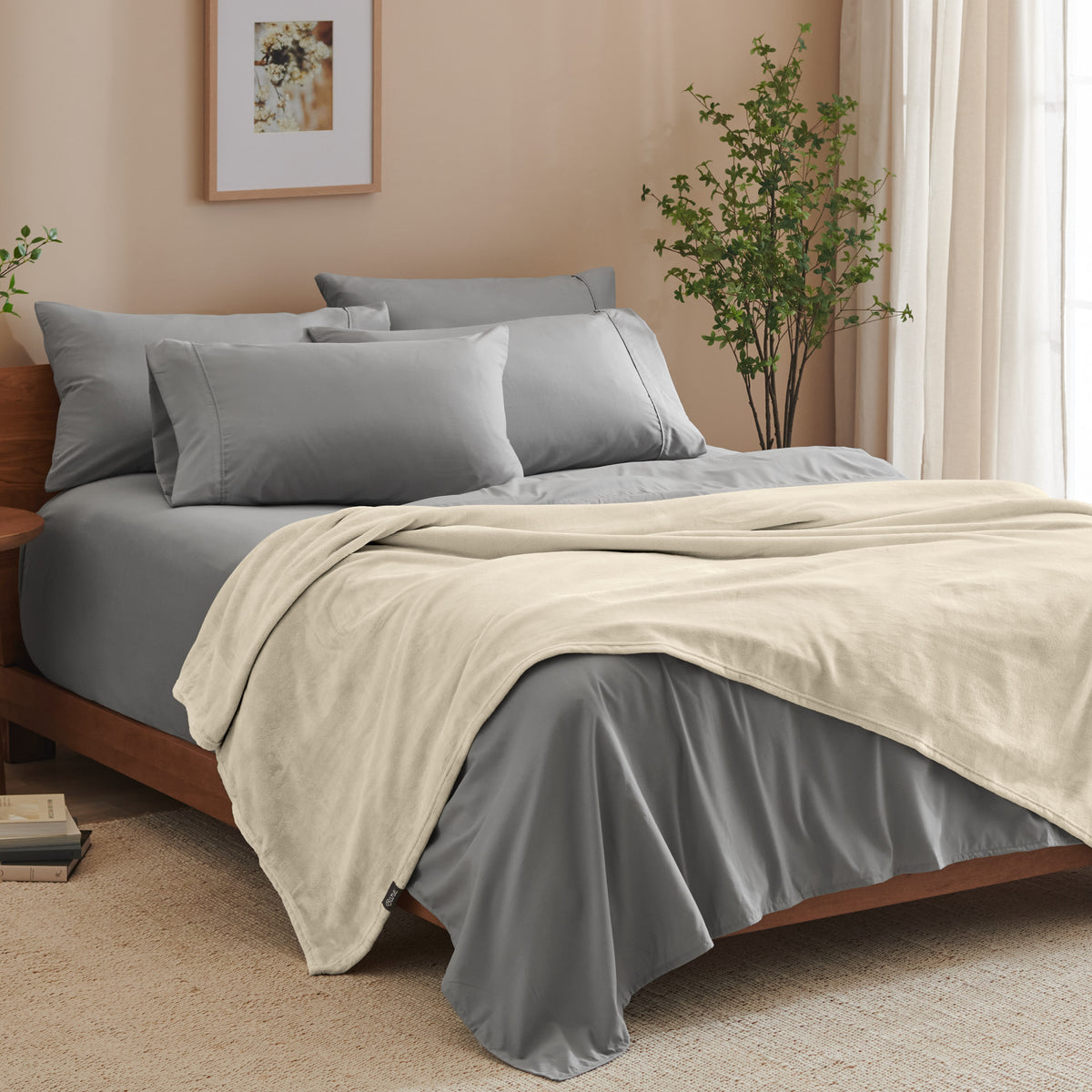 A bed made with grey sheets and a microplush blanket