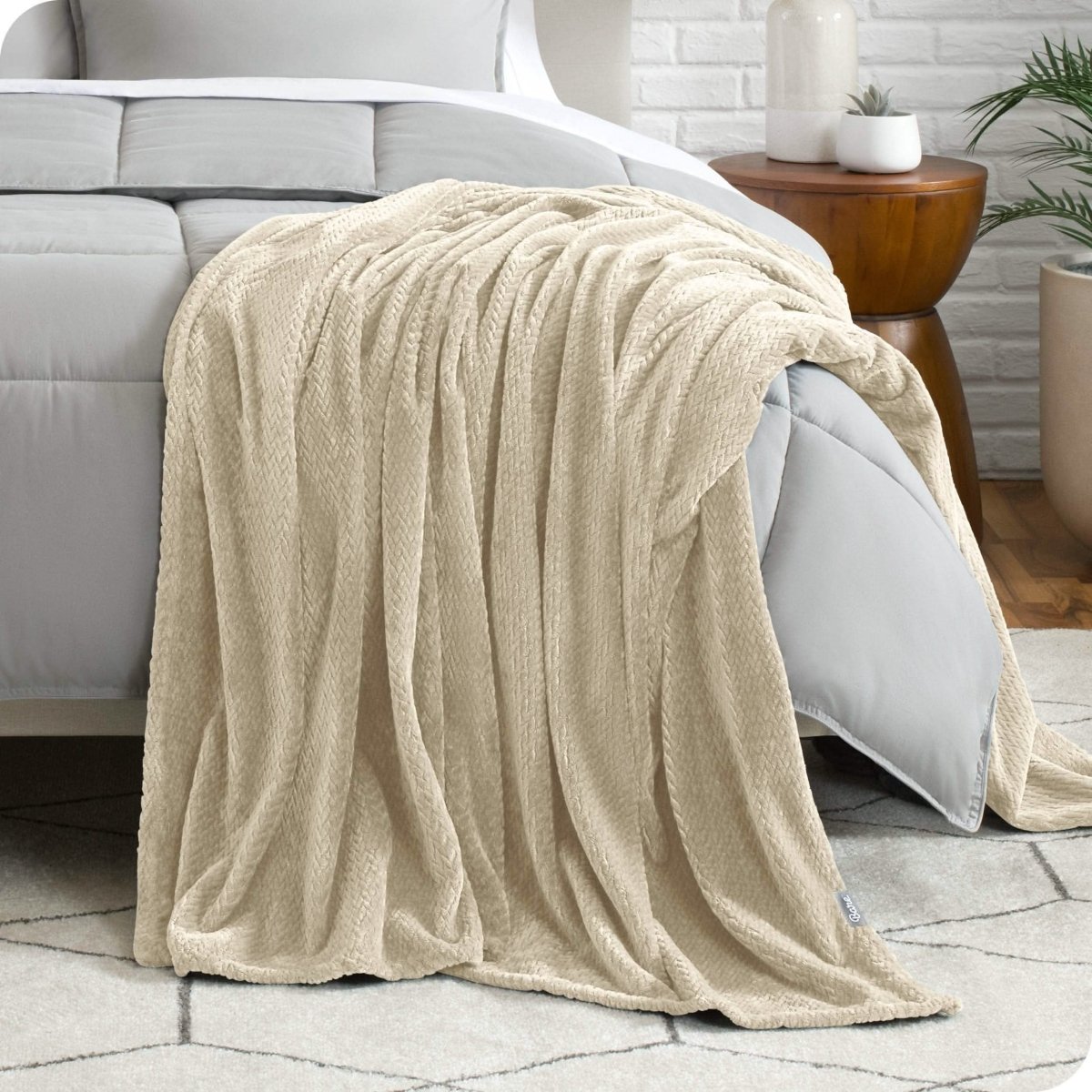 A microplush blanket is draped over the side and bottom of a neatly made bed.