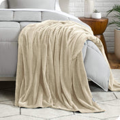 A microplush blanket is draped over the side and bottom of a neatly made bed.