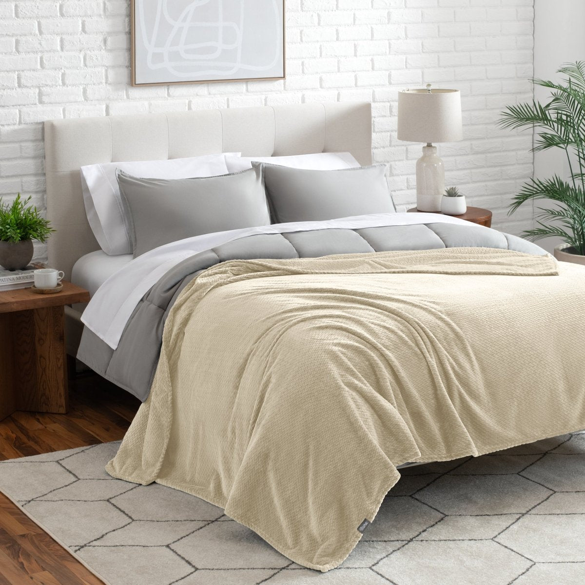 Neatly made bed with a blanket draped over the end of the bed