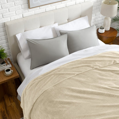 Neatly made bed with a chevron blanket over the comforter